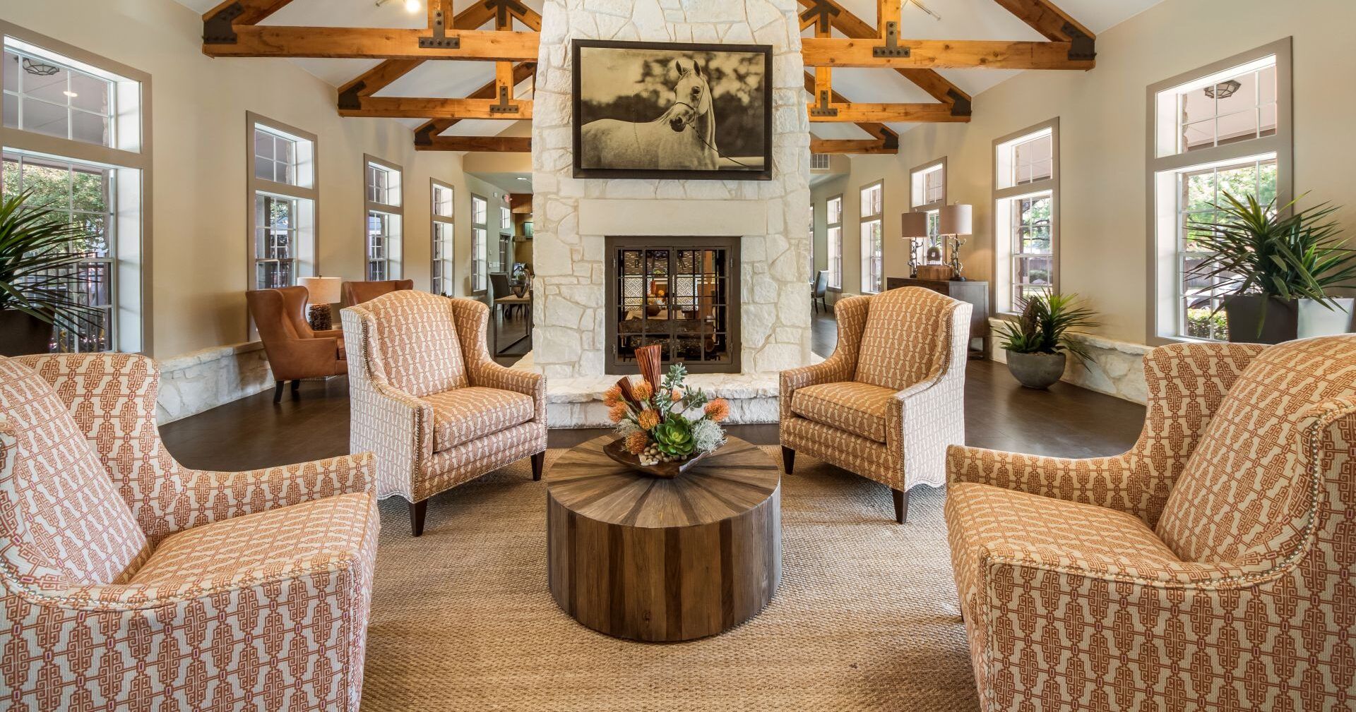 Elm Hollow Apartments community lounge with large stone fireplace, exposed beam vaulted ceilings, and ample comfortable seating areas