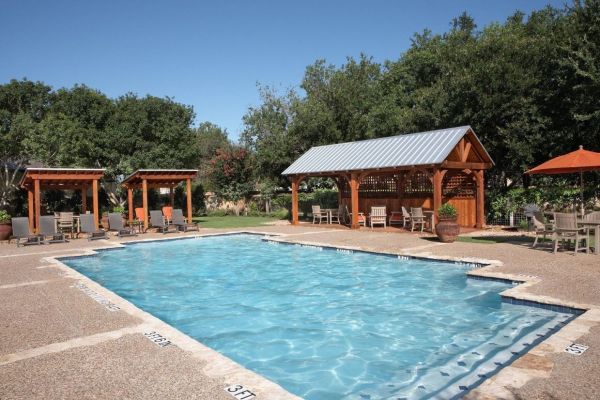 Elm Hollow apartments exterior featuring community pool and outdoor lounge area