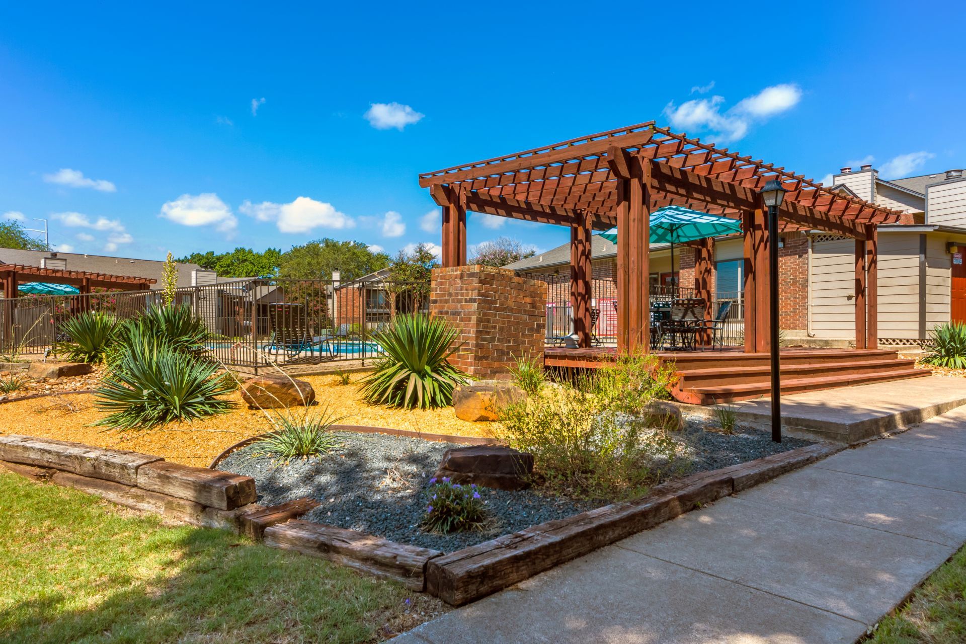 Valley Creek Apartments property exterior with vibrant landscaping and featuring an outdoor community pergola
