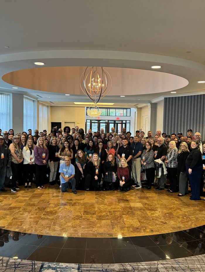 A large group of Amalgamated employees pose together in a ballroom setting.