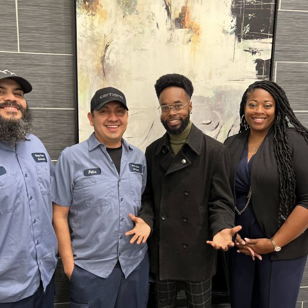 Four employees at Irwin R Rose gather by a large mural