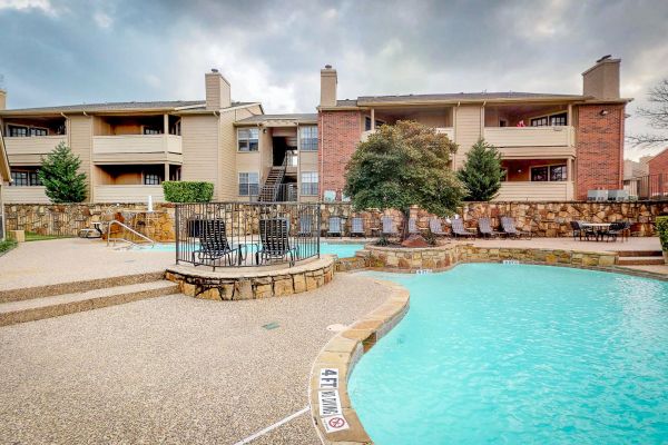 Ashwood Park apartment exterior featuring large community pool and outdoor lounge