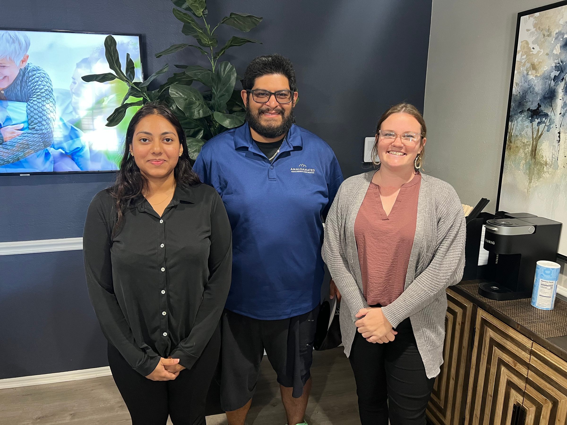 Three people stand in Amalgamated office building