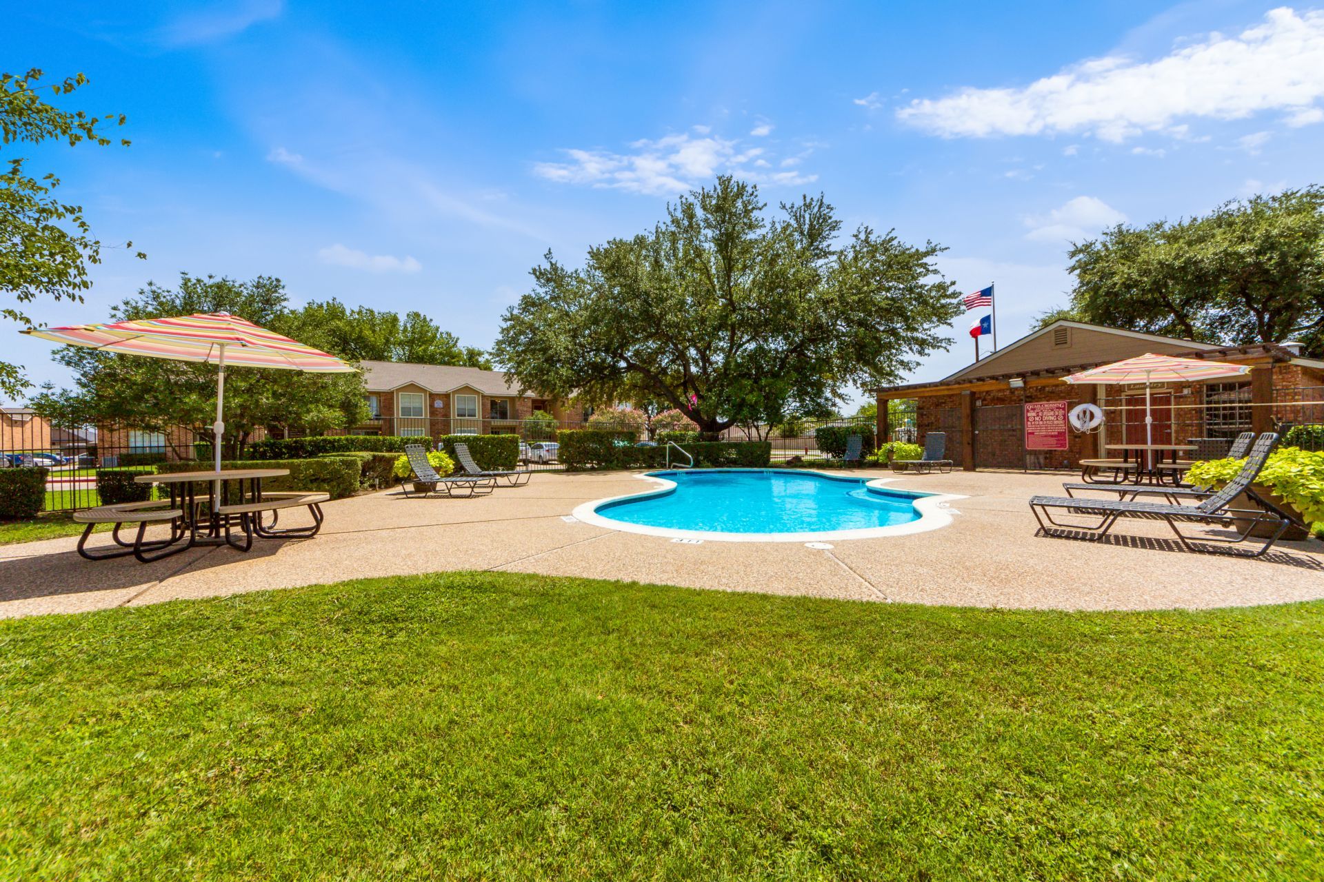 Quail Crossing apartments exterior featuring swimming pool and tanning deck and surrounded by large trees